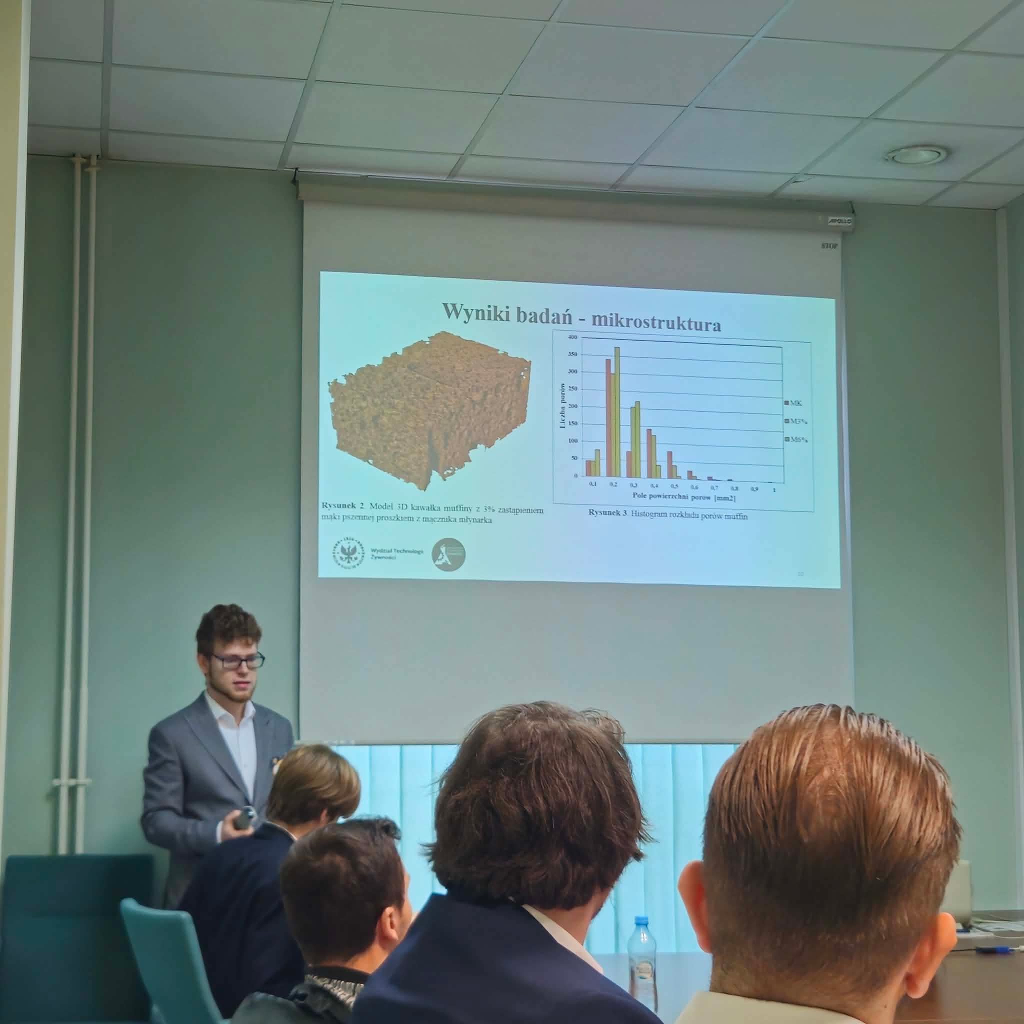 Prelegent przedstawia wyniki badań dotyczących mikrostruktury muffinów podczas sesji naukowej