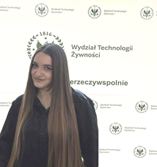Pełnomocnik do spraw social mediów - Olesia Studonowa, stojąca na tle ścianki wydziałowej.