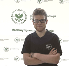 Wiceprezes KNTŻ - Łukasz Dominiak w czarnej koszulce z logo Wydziału Technologii Żywności SGGW, stojący na tle ścianki wydziałowej.